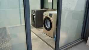 A laundry room with two washing machines and a dryer, a tiled floor, and a glass partition. - Your Lsle Inn (Zhangjiajie)