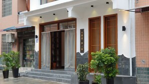 A building with a traditional entrance, potted plants, and a sign with Chinese characters. - Your Lsle Inn (Zhangjiajie)