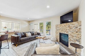 A living room with a fireplace, a sofa, a television, and a dining area. - Dog-friendly mountain condo with washer&dryer (Stateline)