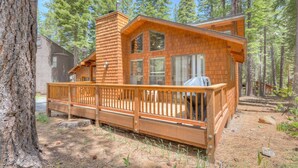A cabin with a deck, surrounded by trees.