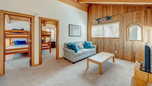 A room with bunk beds, a sofa, a coffee table, and a television.