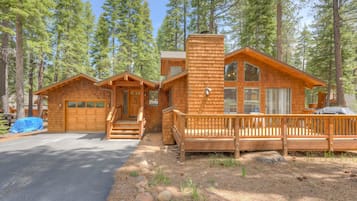 A cabin with a wooden exterior, a front porch, and a garage.
