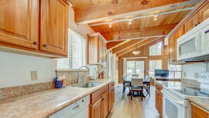 A kitchen with wooden cabinets, granite countertops, a dishwasher, a stove, and a dining area with a table and chairs.