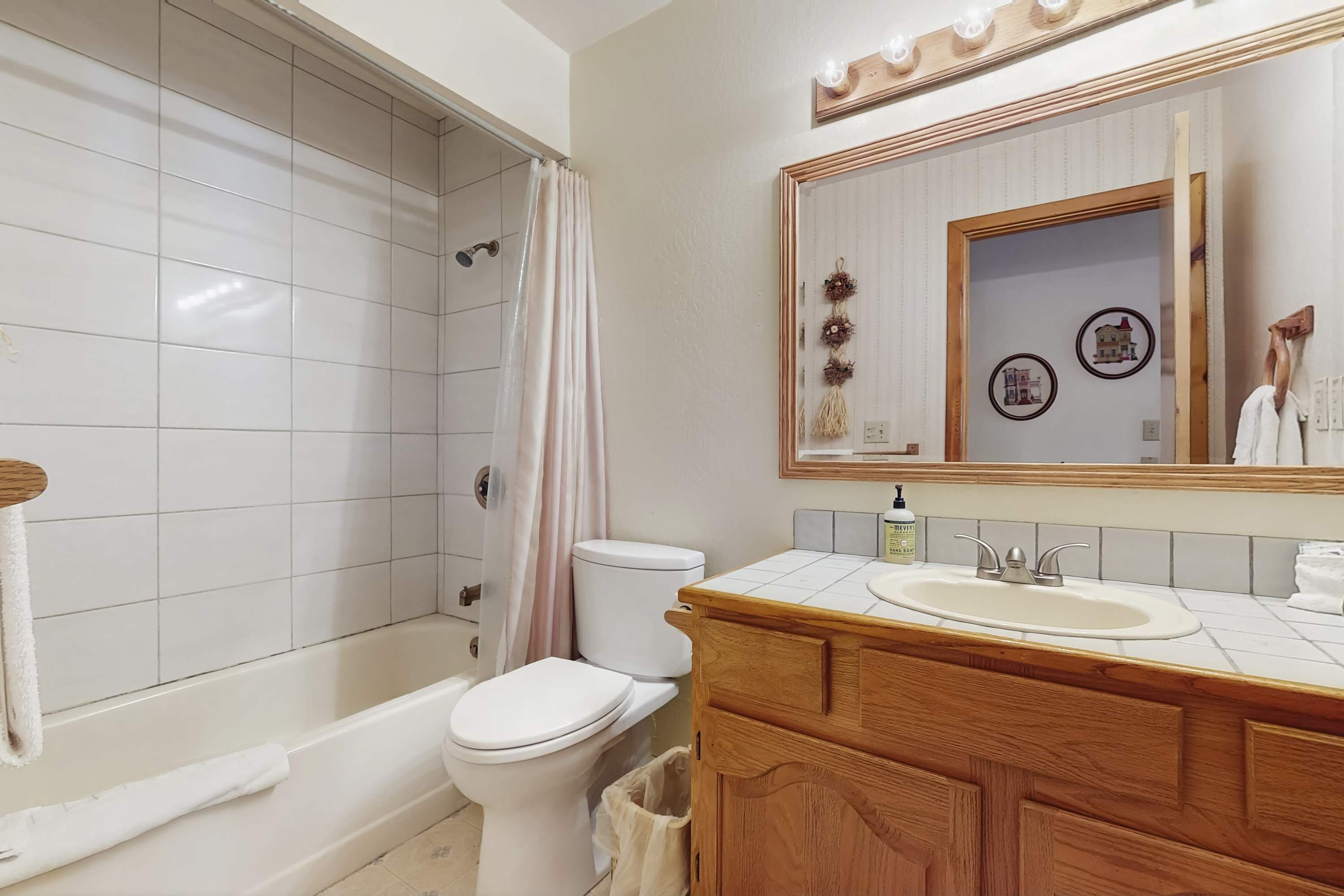 Un baño con bañera, inodoro y tocador con espejo.