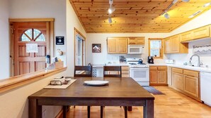A kitchen with wooden cabinets, a dining table, and a microwave. - Modern retreat with wooden touches, shared hot tub, pool, sauna, basket & tennis (Truckee)
