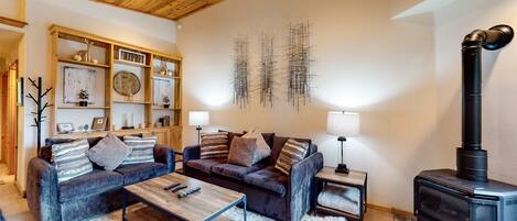 A cozy living room with two sofas, a coffee table, a fireplace, and a wall-mounted shelf with decorative items.