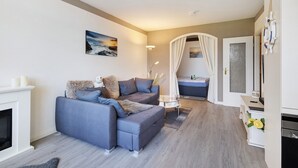Un salon avec un canapé, une table basse en verre, une cheminée et une vue sur l’extérieur.