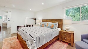 Un dormitorio con cama de madera, mesita de noche, lámpara y vistas al exterior.