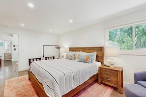 A bedroom with a wooden bed, a nightstand, a lamp, and a view of the outdoors. - Cozy & contemporary, family-friendly home with free WiFi & a private washer&dryer (Tahoe City)