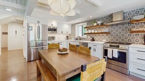 Una cocina moderna con electrodomésticos de acero inoxidable, una mesa de comedor de madera y un salpicadero con diseño.