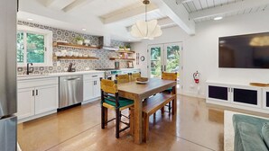 Una cocina moderna con armarios blancos, una mesa de comedor de madera y un ventanal grande.