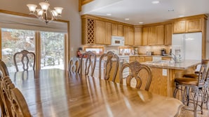 A spacious kitchen with wooden cabinets, a central island with bar stools, a dining table with chairs, and a chandelier. - Three-story lakefront home with lake views, wood fireplace, high-speed WiFi, W&D (Soda Springs)