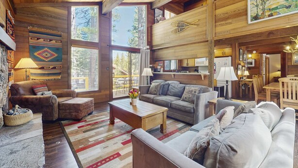 A spacious living area with a fireplace, wooden ceiling, and large windows. - Spacious Northstar Lake Retreat – Perfect for Families & Groups ️ (Truckee)
