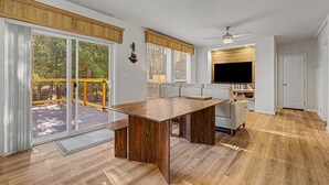A modern kitchen with a large island, sliding glass doors to a deck, and a ceiling fan.