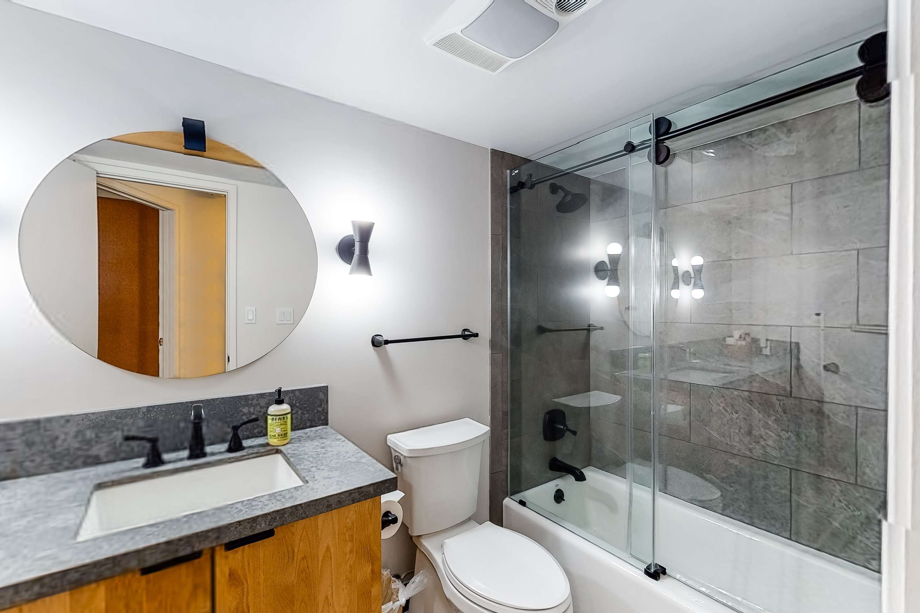 Une salle de bain moderne avec une douche à parois de verre, un lavabo doté d’un plan de toilette en marbre et des toilettes.