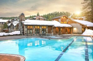 Ein Resort mit Schwimmbad, Steinbauten und schneebedeckten Dächern.