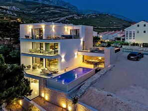 A modern two-story house with a swimming pool, outdoor seating, and a view of the surrounding landscape. - Stay With Pool in Promajna (Baska Voda)