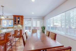 A spacious kitchen with wooden cabinets, a large dining table, and bar stools. - Updated Retreat with Game Room, Pool Table & Foosball (South Lake Tahoe)