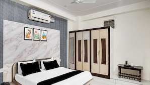 A bedroom with a bed, an air conditioning unit, a wardrobe, and a bedside table. - Deluxe Hotel Chinar (Jaipur)