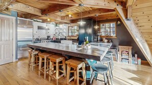 Una cocina amplia con una isla grande, taburetes de madera y un techo alto con vigas a la vista.