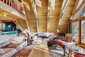 A cozy cabin interior with a wooden ceiling, a sofa, a chair, and a dining table. - Luxury lakefront home with private hot tub, on-site dock, fireplace & HOA beach (Soda Springs)
