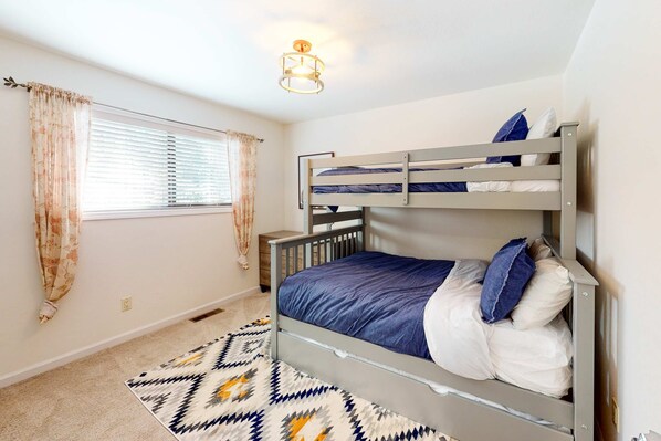 Dormitorio con literas, alfombra estampada, cortinas y lámpara de techo.