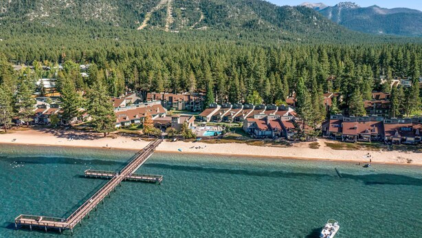 A coastal resort with a pier, beachfront villas, and a mountain backdrop.