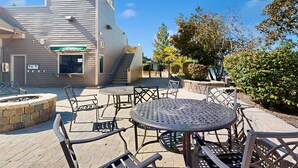 A patio area with outdoor seating, a fire pit, and a building with a staircase.