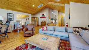 Una sala de estar amplia con techo de madera, un sofá, una mesa de centro y una chimenea.