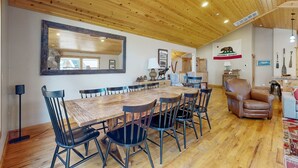 Un comedor con una mesa y sillas de madera, un espejo grande y la bandera de la República de California.
