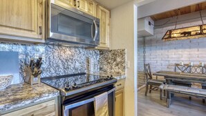 Una cocina con estufa de acero inoxidable, armarios de madera y salpicadero de mármol.