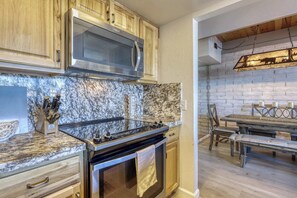 A kitchen with a stainless steel stove, wooden cabinets, and a marble backsplash. - Tahoe Keys Waterfront Escape (South Lake Tahoe)