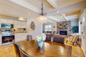 A spacious kitchen with white cabinets, a dining area with a wooden table, and a brick fireplace. - Beautifully Updated Home - 10 Minutes to Heavenly & Beach (South Lake Tahoe)