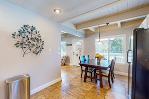 Cuina amb taula de dinar, cadires, nevera i un objecte decoratiu a la paret.