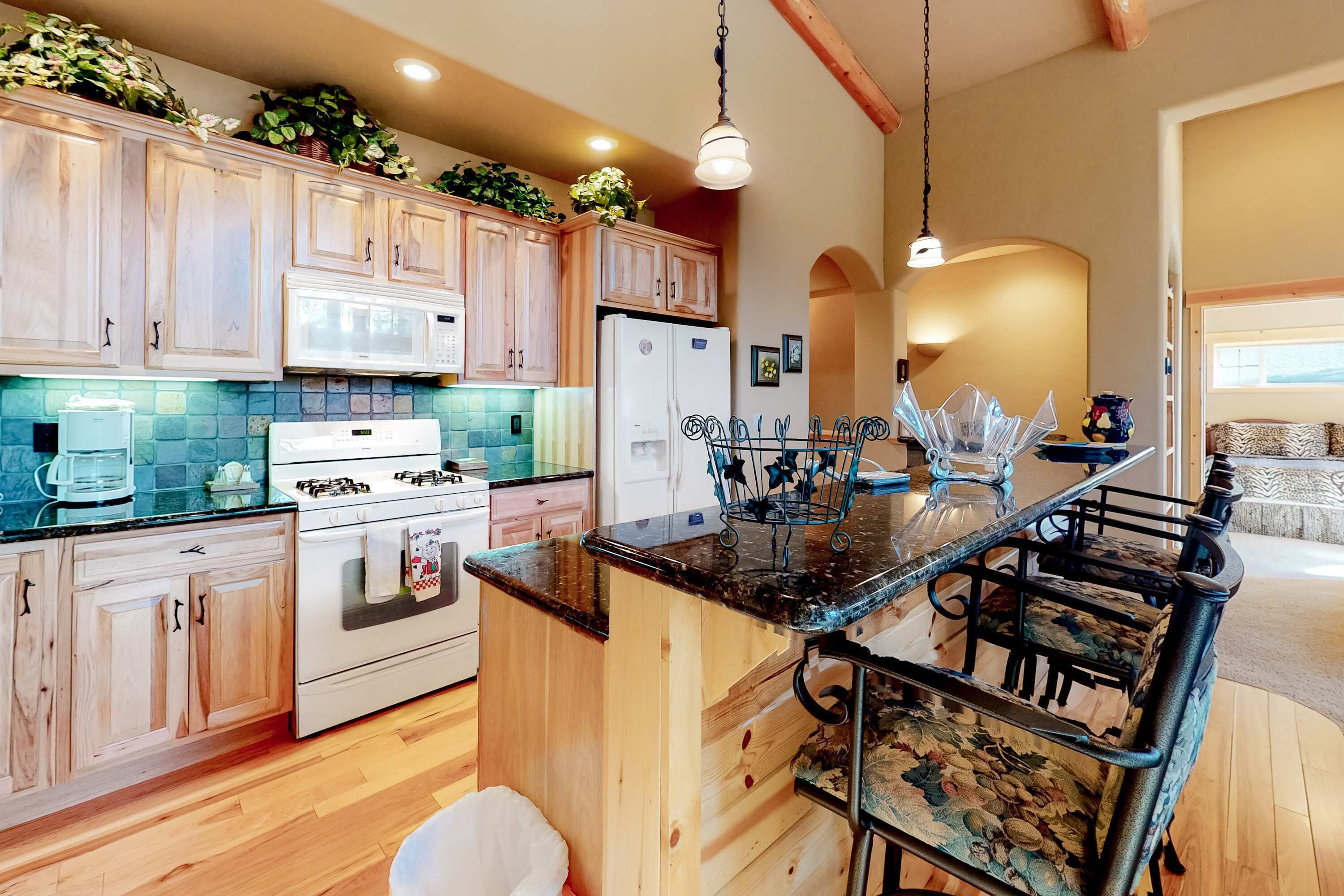 A kitchen with wooden cabinets, a central island with bar stools, a refrigerator, and a microwave.
