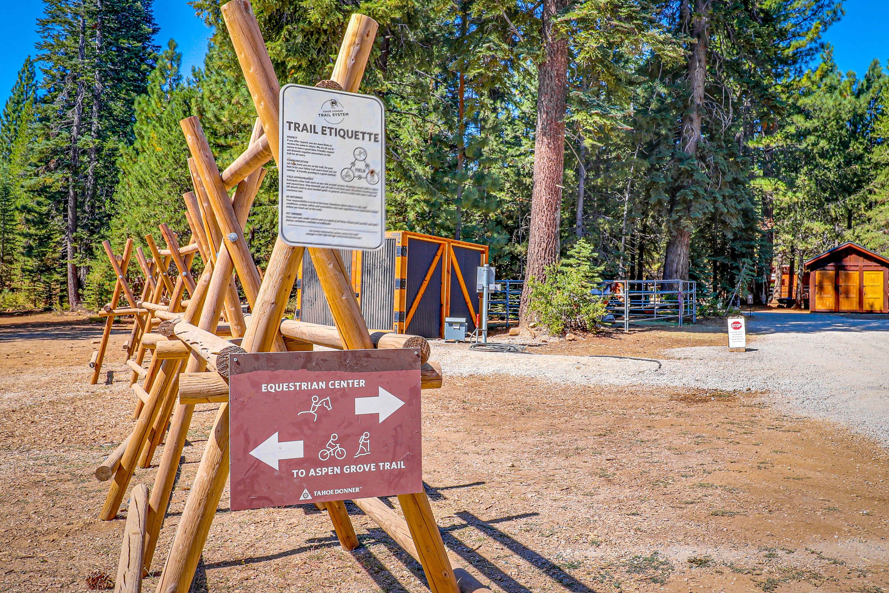 A wooden signpost with trail etiquette information and directional arrows for the Equestrian Center and Aspen Grove Trail.