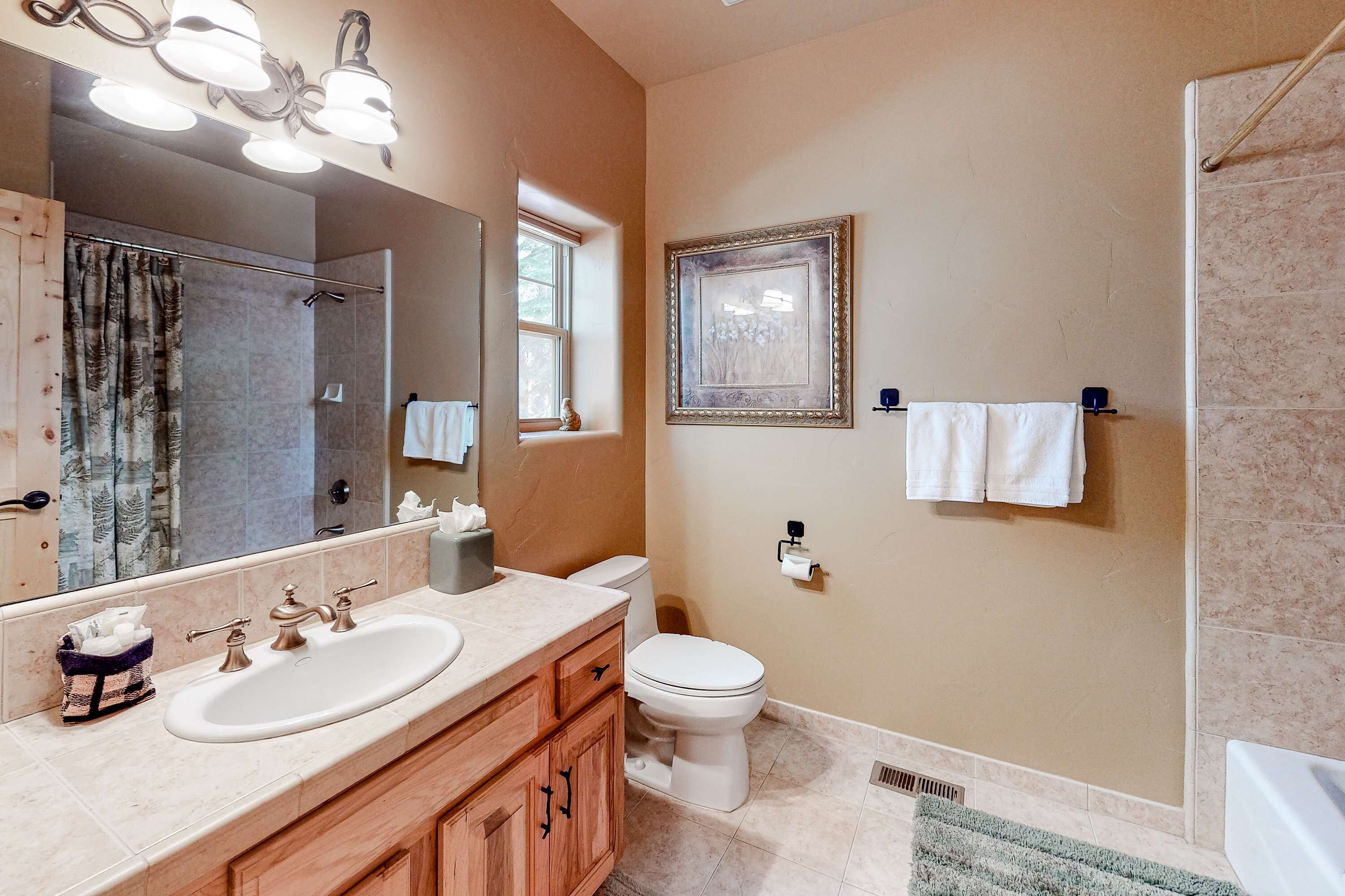 A bathroom with two sinks, a toilet, a shower, and a large mirror.