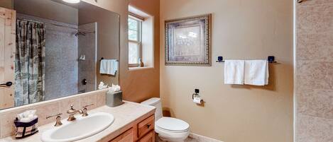 A bathroom with two sinks, a toilet, a shower, and a large mirror.