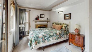 Un dormitorio con cama, cómoda, chimenea y ventana con cortinas.