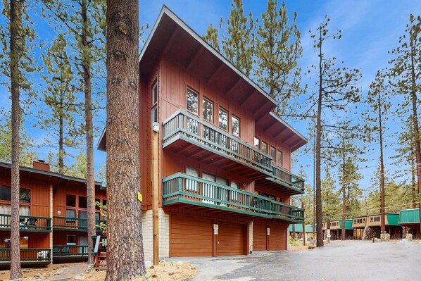 A multi-story lodge with balconies, wooden exterior, and a parking area.
