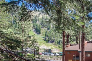 A building with a flat roof, surrounded by tall trees and a hilly landscape. - Slopeside alpine condo with gas fireplace, shared hot tub-at base of Heavenly Lodge (South Lake Tahoe)