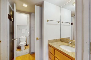 A bathroom with a toilet, sink, and mirror.