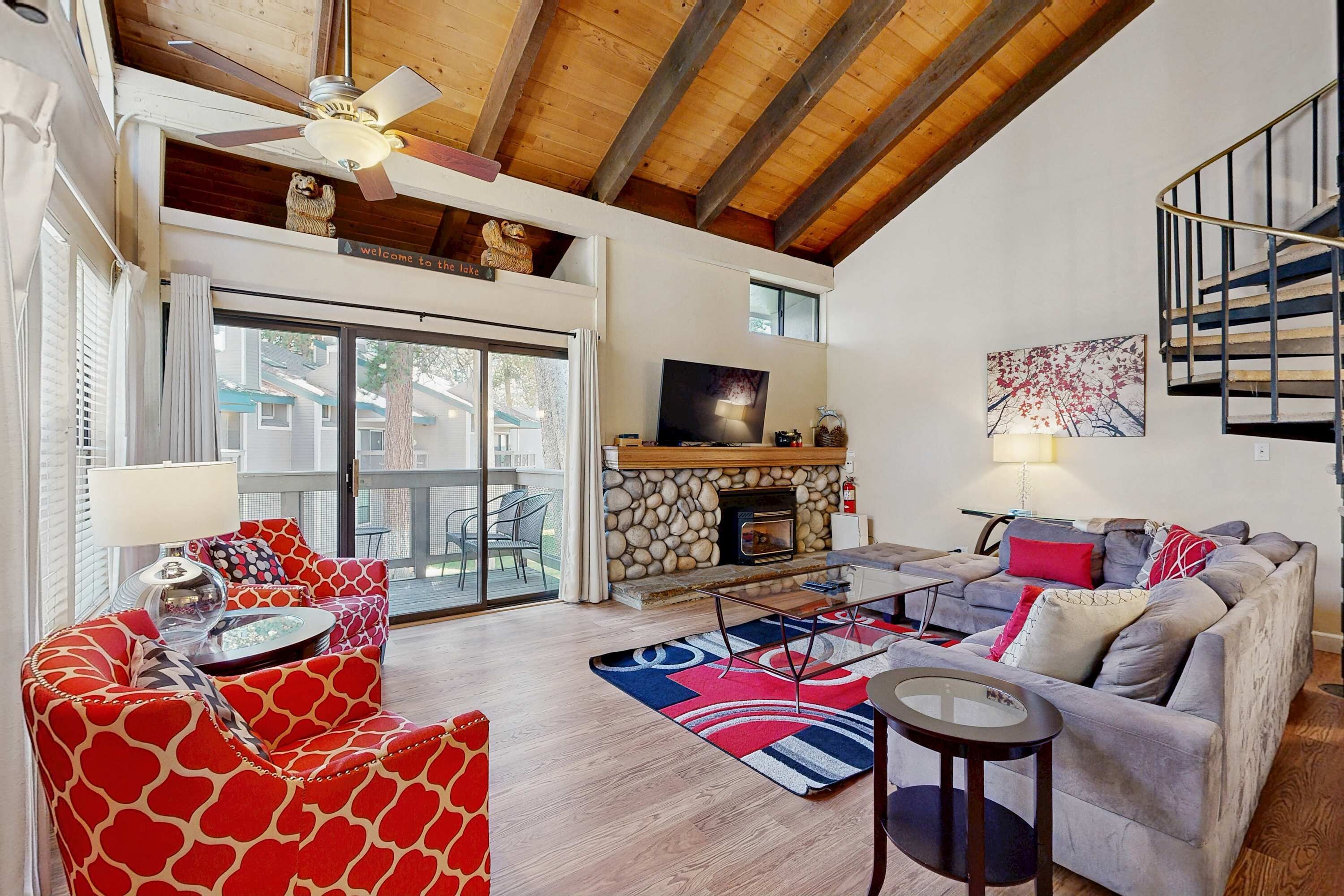 A spacious living room with a fireplace, a ceiling fan, and a staircase.