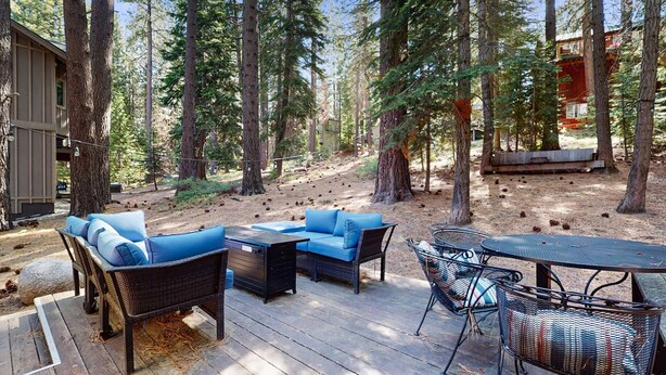 A deck with outdoor furniture, surrounded by tall trees. - Cozy, dog-friendly cabin with large private deck, fireplace, BBQ-close to trails (South Lake Tahoe)