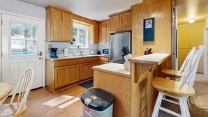 A compact kitchen with wooden cabinets, a stainless steel refrigerator, a sink, and a window. - Cozy, dog-friendly cabin with large private deck, fireplace, BBQ-close to trails (South Lake Tahoe)