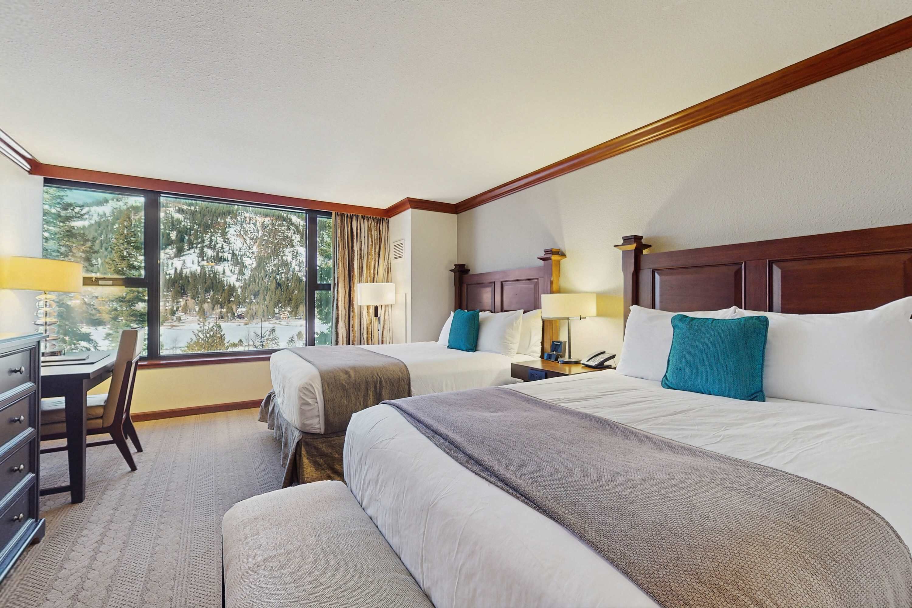 A hotel room with two beds, a desk, and a chair.