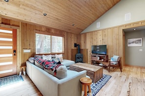 A wooden-paneled living room with a sofa, a television, a fireplace, and a wooden coffee table. - private hot tub & fenced yard - walk to beach (Tahoma)
