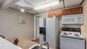 Une cuisine équipée d’une cuisinière, d’un four à micro-ondes, d’un réfrigérateur et d’un plan de travail en granit.