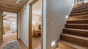 Un escalier dont les marches sont recouvertes de moquette, menant à une pièce où se trouvent un bureau et une chaise.