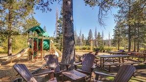 A playground with slides and a climbing structure, surrounded by picnic tables and Adirondack chairs. - Spacious home with private hot tub & game room - near skiing, hiking, biking (Truckee)